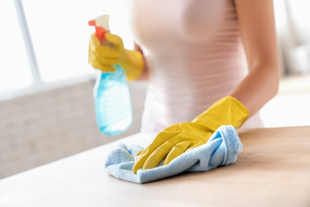 Close up of female housekeeper specialist hold blue duster cleaning table