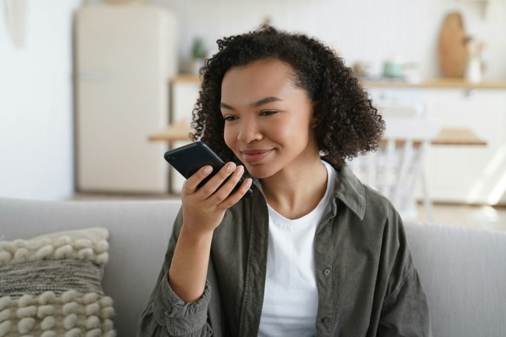 Mixed race teen girl holding phone, speak voice message, use intelligent personal virtual assistant